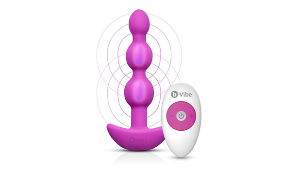 On a white background, the B vibe Triplet anal beads sex toy with its remote controller. The toy is a vibrant pink color.