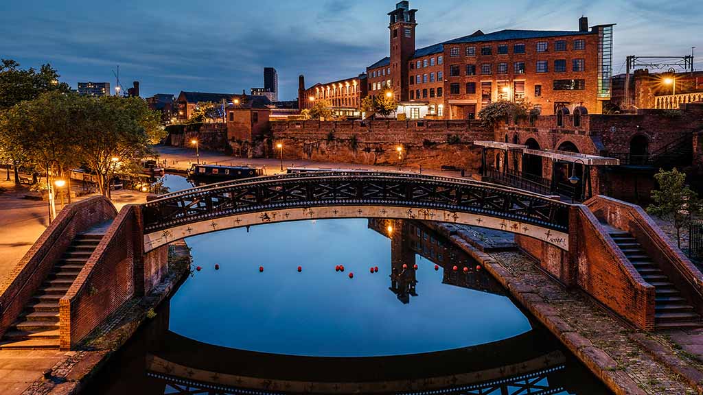 A romantic bridge over a river in Manchester during the evening