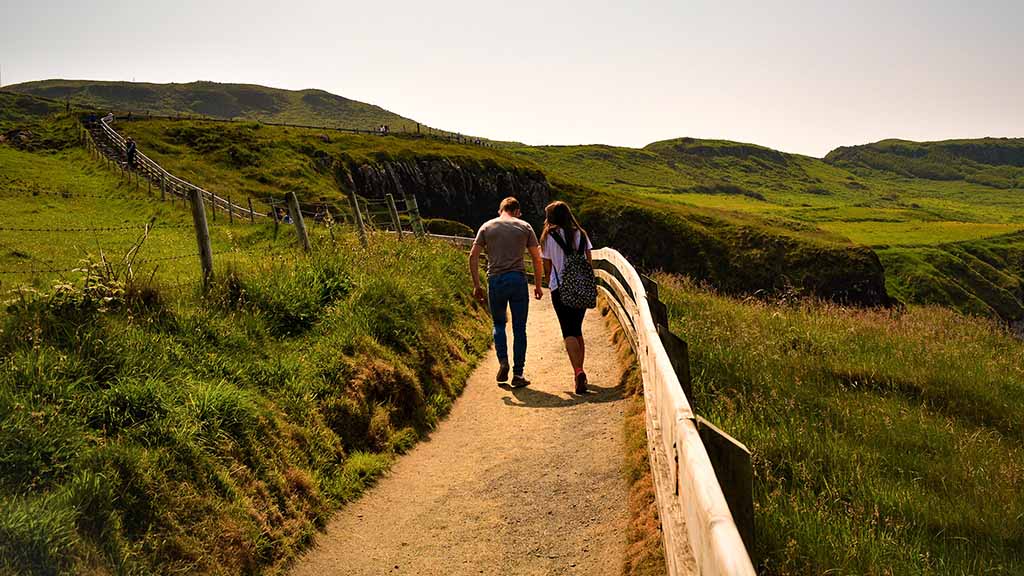 A man and a woman with backpack holding hands walking in the countryside